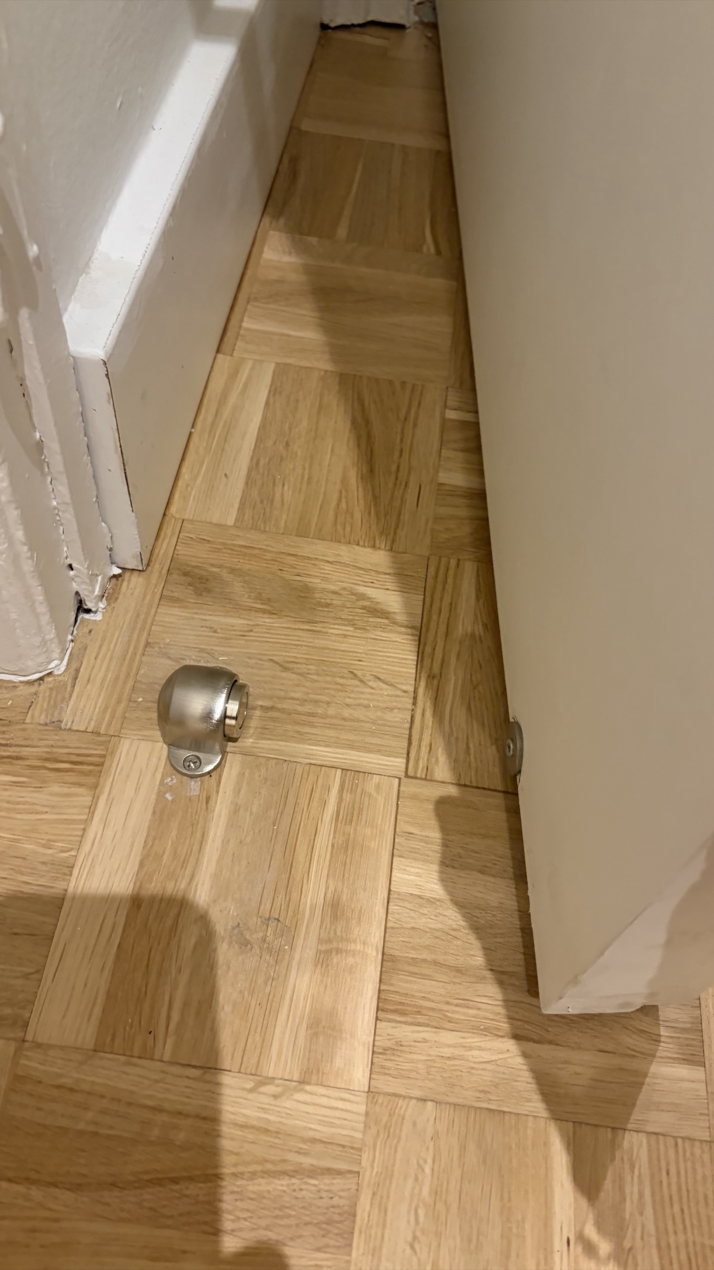 Magnetic door stop installed on wooden floor near the door corner