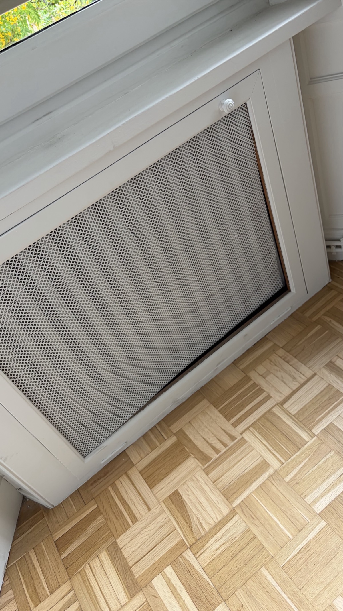 Radiator cover with metal honeycomb mesh grille, seen at an angle during the repair