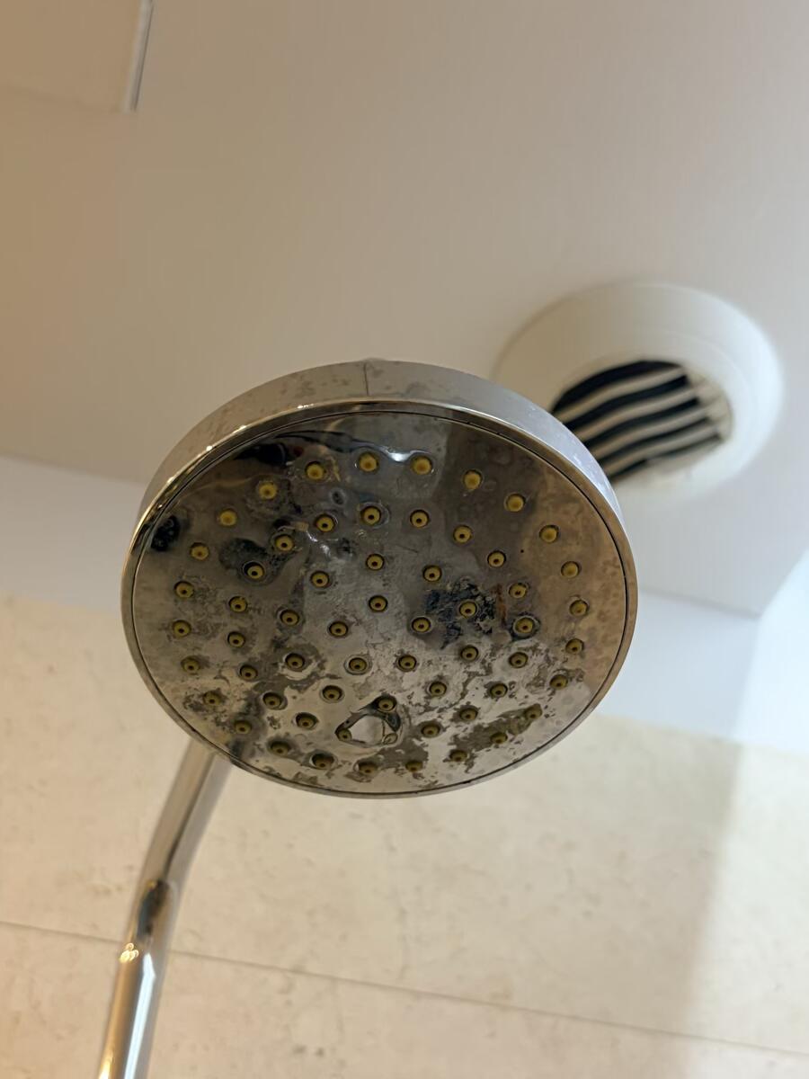 Shower glass door with visible hard water mineral stains and cloudy film