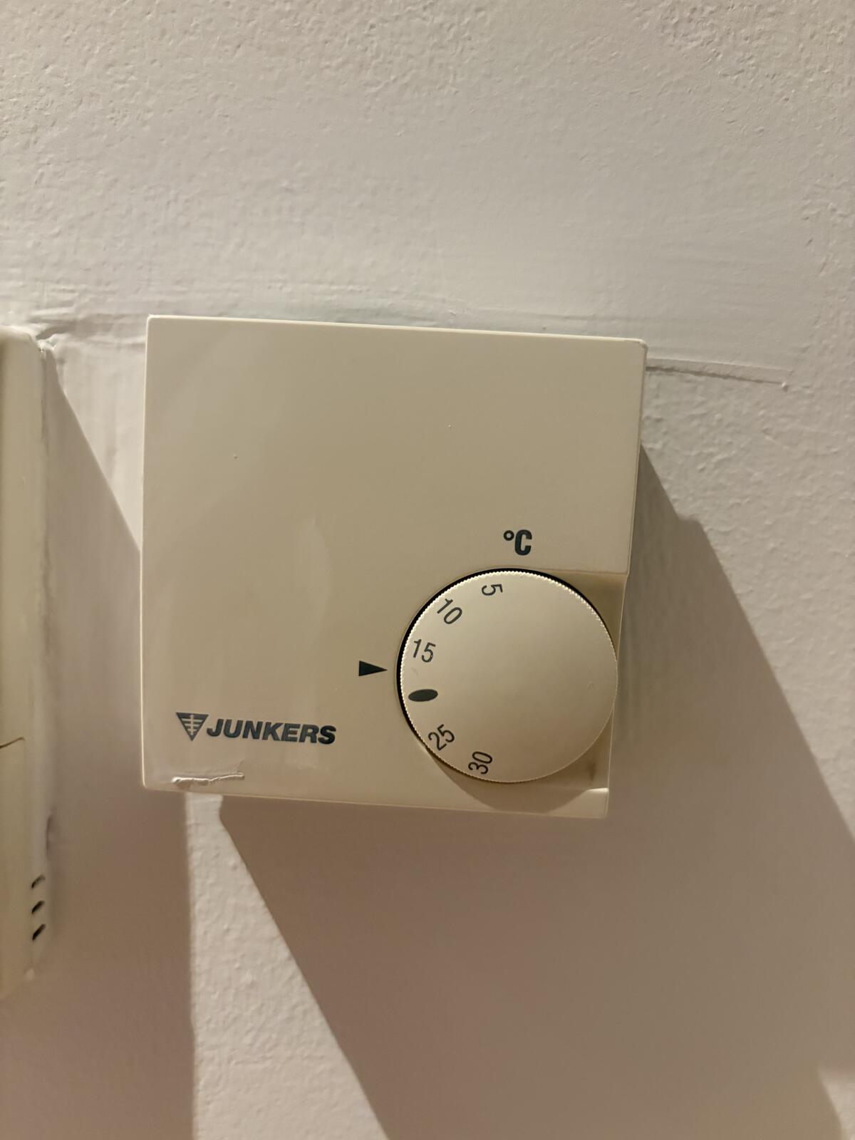 Wall-mounted thermostat showing temperature display and mode controls